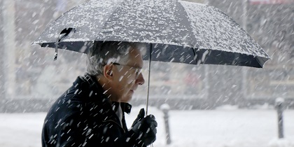 Elderly man walking alone under umbrella snowy city street in heavy snowfall