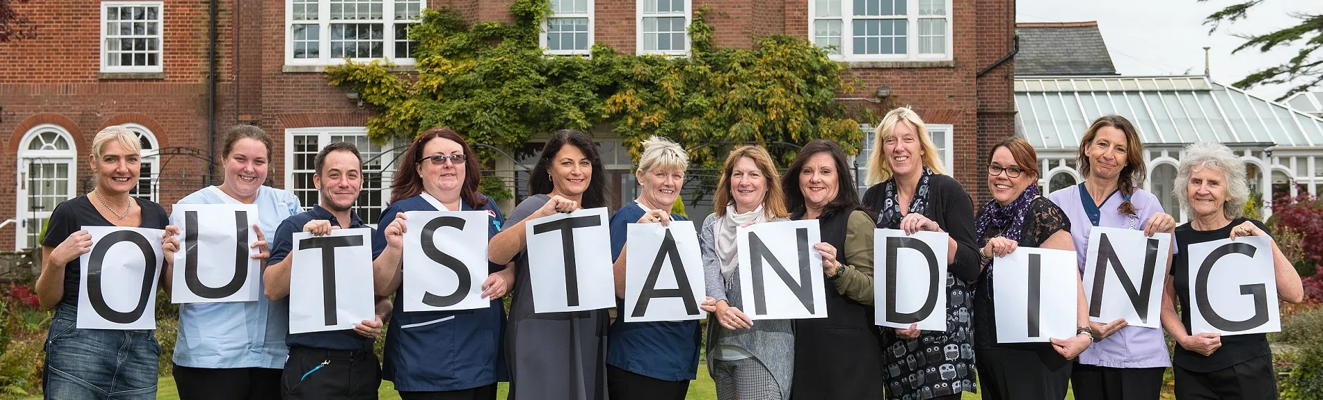 Greensleeves celebratory team holding letters that spell outstanding