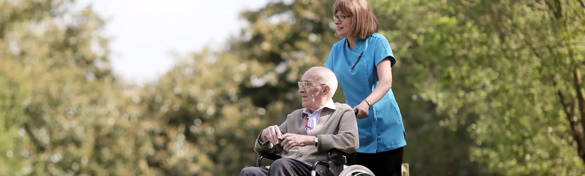 A group of senior individuals sitting together and conversing in a garden environment.