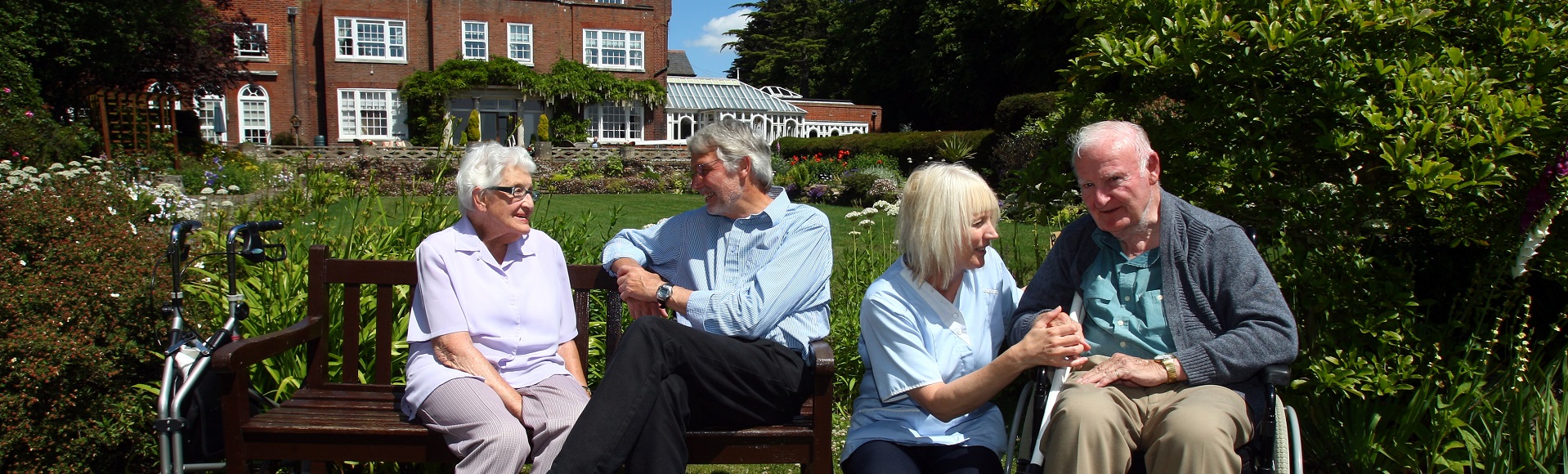 A group of senior individuals sitting together and conversing in a garden environment.